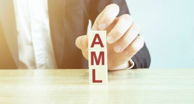 A man in a suit is stacking letter blocks to spell "AML".